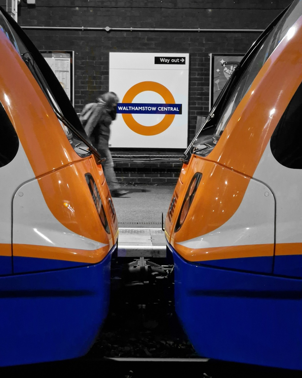 Two train ends face each other, the orange and blue are the only colours, this is repeated by the train station logo.