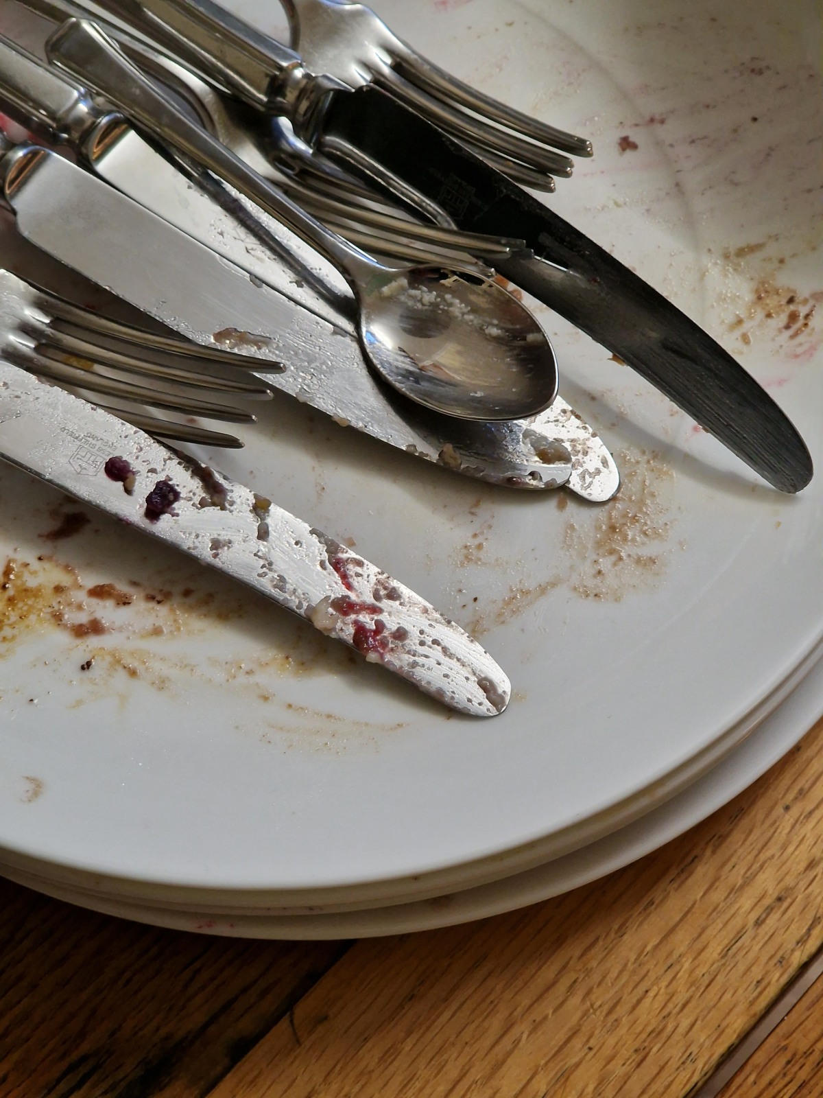 Dirty knives, forks and spoons on a pile of dirty plates.